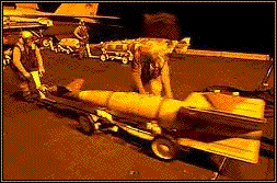 Aviation Ordnancemen move a 1,000-pound bomb onto the flight deck aboard the aircraft carrier USS Carl Vinson.